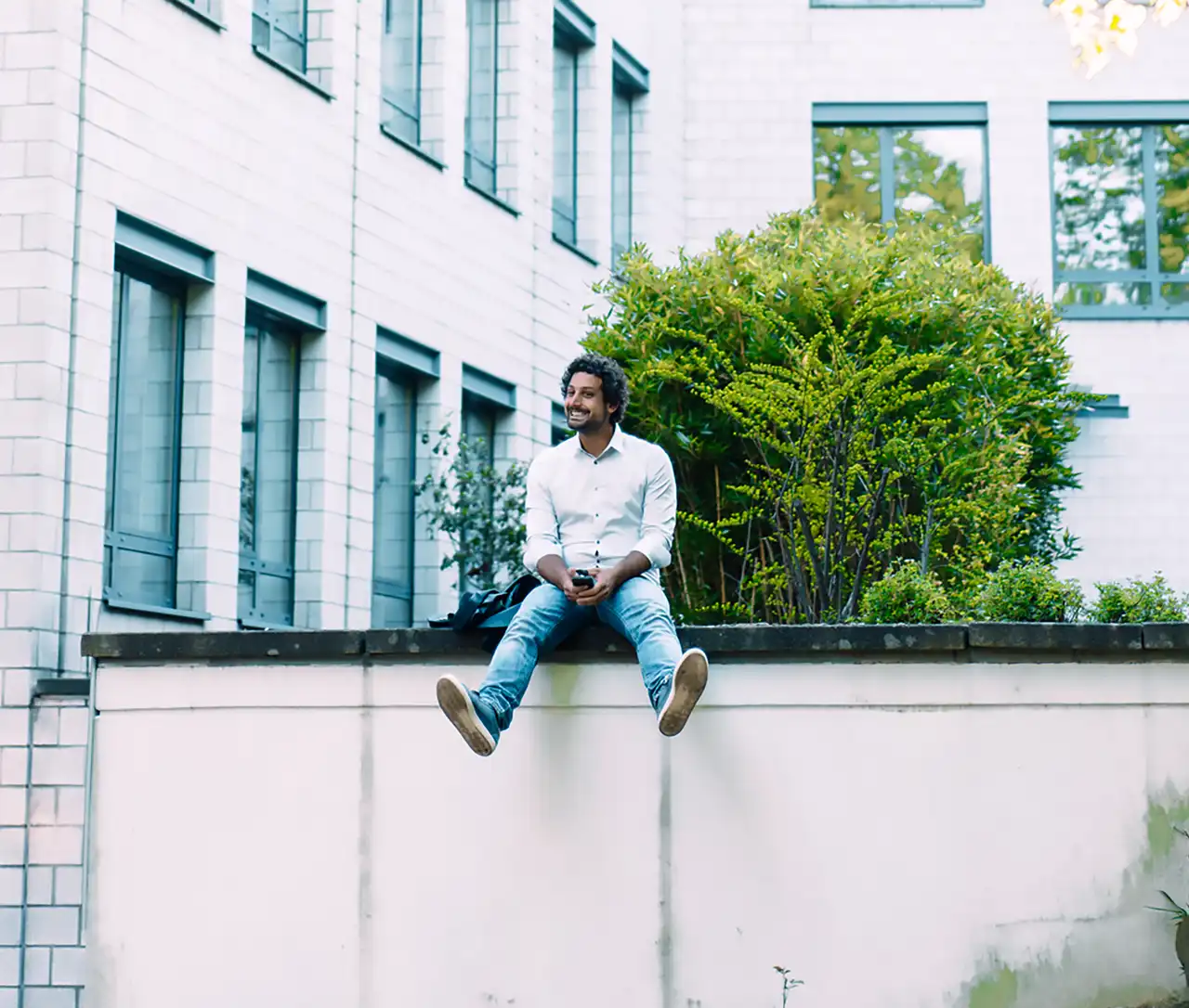 Mann sitzt auf Mauer